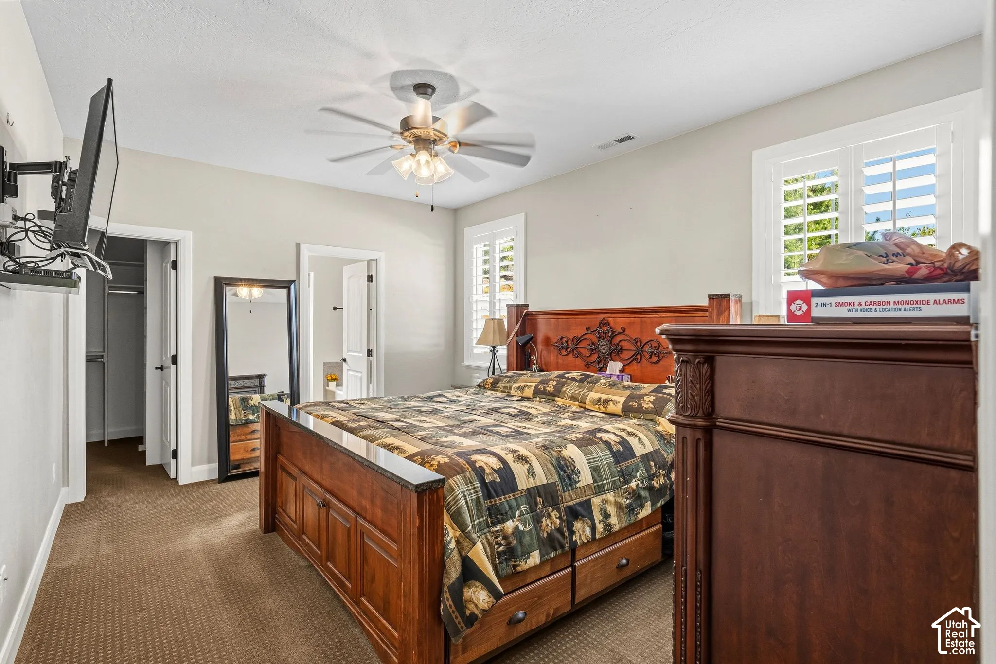 Carpeted flooring, ceiling fan with light fixture, plantation shutters, and a built-in closet