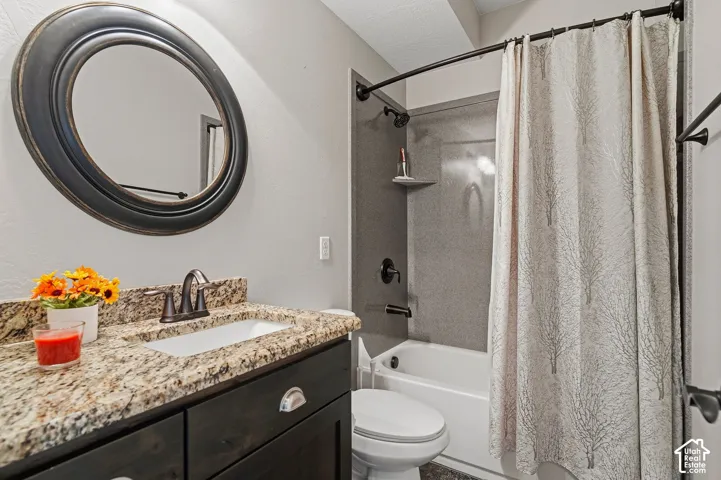 Vanity with granite-style countertop, undermount sink, and dark wood-finish cabinetry