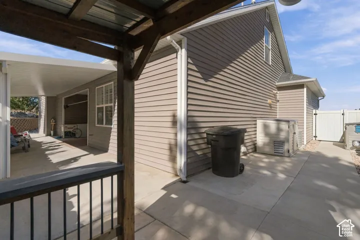 Expansive covered patio with concrete flooring, wood support beams, and a black metal railing