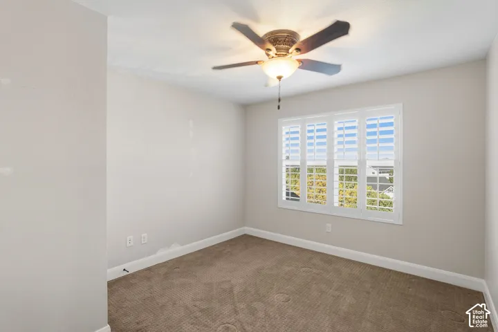 Ceiling fan with integrated lighting, window with plantation shutters, neutral-toned walls, and carpet flooring