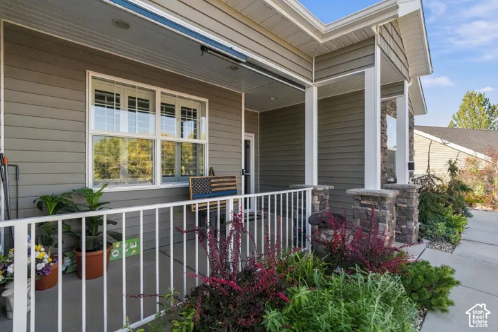 Covered front porch featuring white railing, stacked stone column bases, and horizontal siding