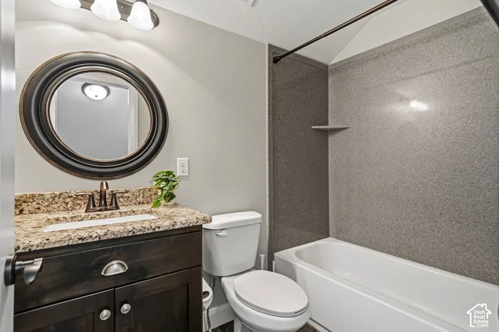 Vanity with a stone-finish countertop, undermount sink, and dark wood-finish cabinetry