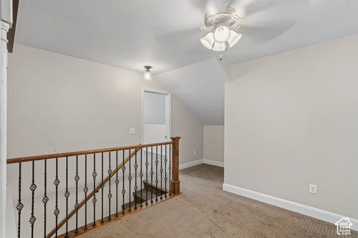 Carpeted landing with a decorative wrought iron and wood railing, recessed ceiling light, and a ceiling fan