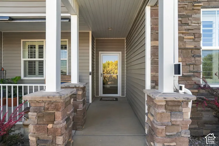 Entryway featuring stone-clad columns, white railing, and horizontal siding