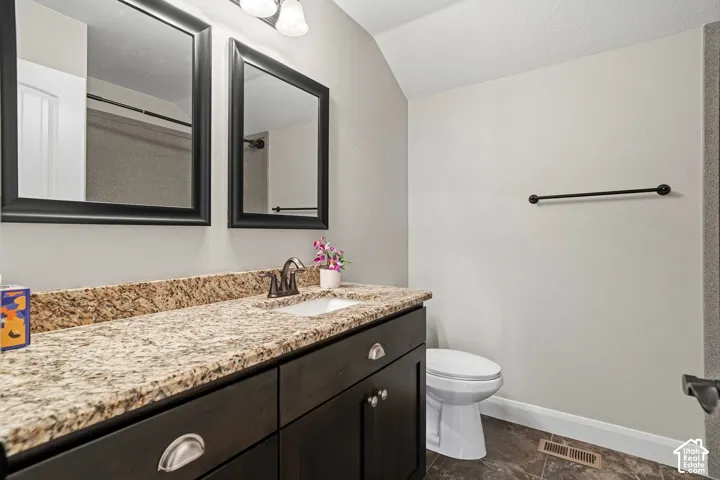 Vanity with a granite countertop, integrated sink, and dark wood-finish cabinetry