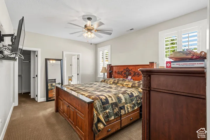 Carpeted flooring, ceiling fan with light fixture, plantation shutters, and a built-in closet