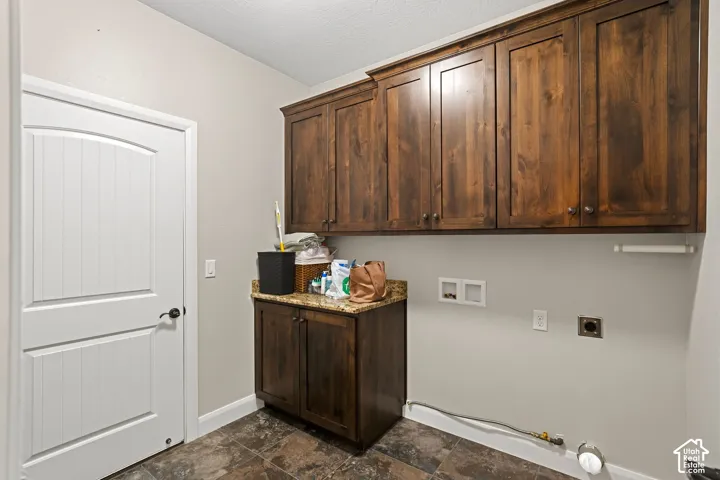 Dedicated utility room featuring rich wood cabinetry with ample storage, stone-finish flooring, and a central island with countertop workspace