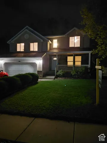 Two-story residence featuring a covered front porch, integrated garage, and a manicured front lawn