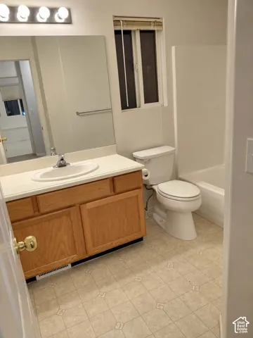 Vanity with wood-finish cabinetry, white countertop, and integrated sink