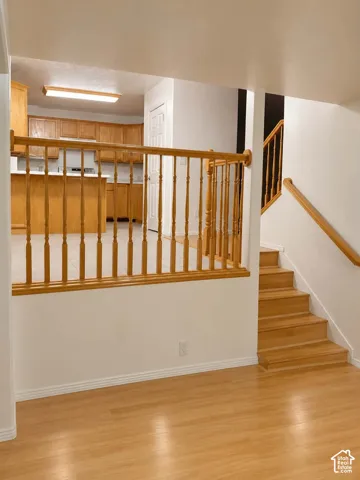 Wood-finish flooring, staircase with wood banister, kitchen with wood cabinetry, and a kitchen island