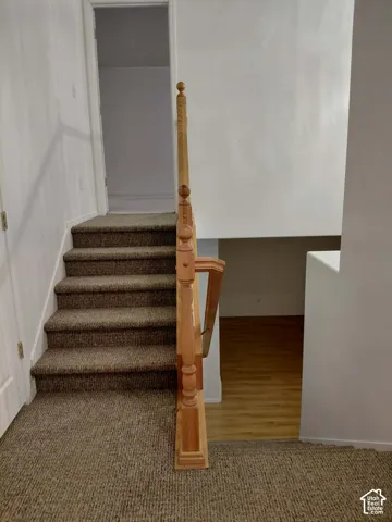 Carpeted staircase with a wood-finish newel post and railings