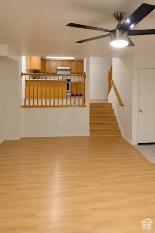 Spacious interior with wood-finish flooring, a contemporary ceiling fan, and a wood railing system