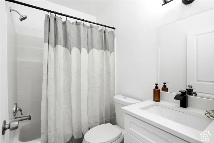 White vanity with an integrated sink, black waterfall-style faucet, and a wall-mounted mirror