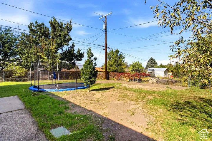 Expansive yard space featuring a concrete patio, mature trees, and a utility shed