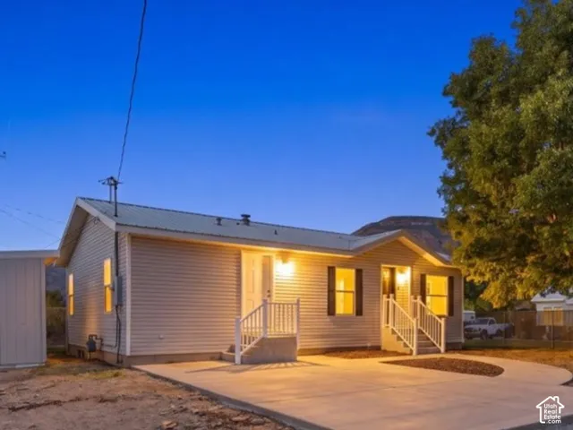 Siding exterior with a covered entry, metal roof, and concrete patio