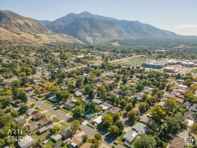 Expansive residential area with a prominent mountain backdrop, featuring a public school building, athletic fields, and numerous mature trees