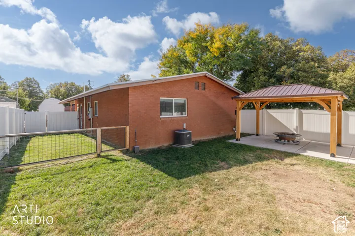 Brick exterior with a covered patio featuring a metal roof, a white privacy fence, and a designated fenced area