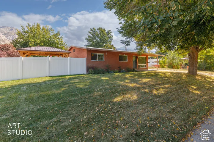 Single-story brick exterior with a large front lawn, mature trees, and a covered porch
