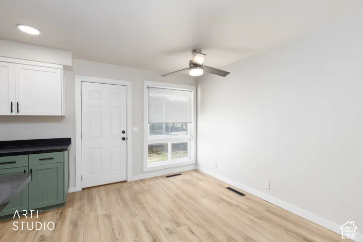 Wood-finish flooring, white walls, and a window with a roller shade