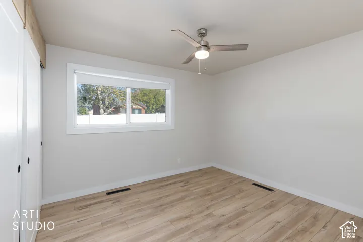 Wood-finish flooring, white walls, and a ceiling fan with integrated lighting