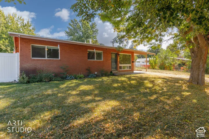 Red brick exterior with white trim, large picture window, covered front entrance, and mature trees on a grassy lot