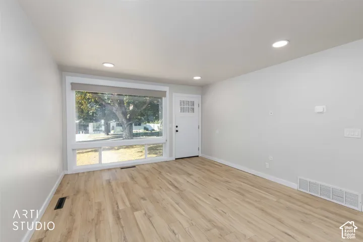 Wood-finish flooring, recessed lighting, and a white paneled entry door