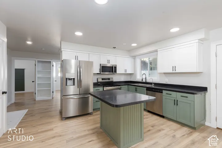 Kitchen featuring an island, stainless steel appliances, wood-finish flooring, recessed lighting, and a window