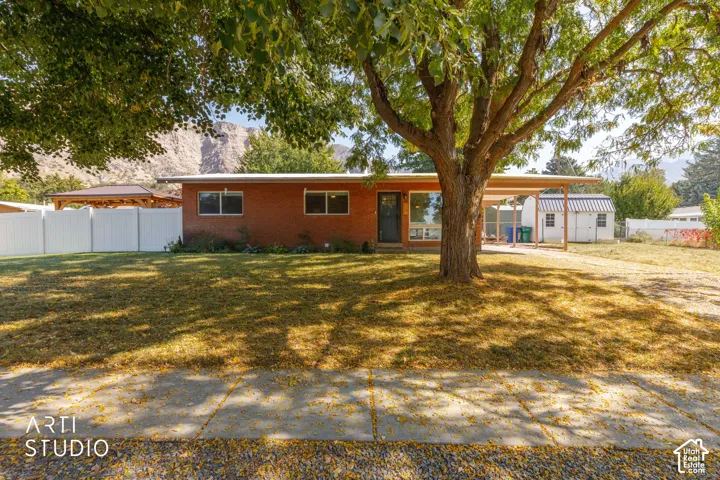 Brick exterior, carport, mature trees, mountain backdrop, white privacy fencing