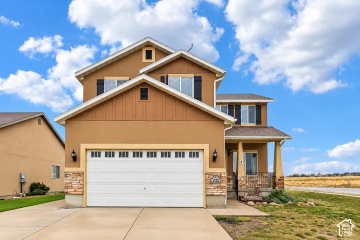 Two-story exterior featuring a stucco facade, stone veneer accents, a multi-gabled roofline, and an attached two-car garage