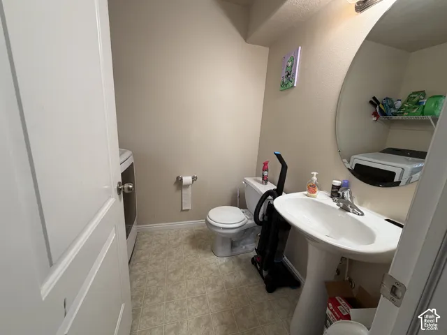 Pedestal sink with a chrome faucet, oval mirror, and tile-finish flooring
