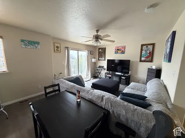 Living area with wood-finish flooring, a ceiling fan, and a glass sliding door providing outdoor access
