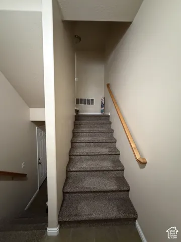 Carpeted staircase with a wood-finish handrail