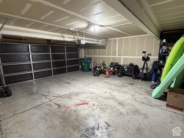 Garage featuring a sectional overhead door with panels and an automatic opener