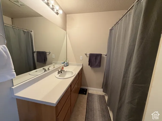 Bathroom vanity with integrated sink, long mirror, and polished chrome light fixture