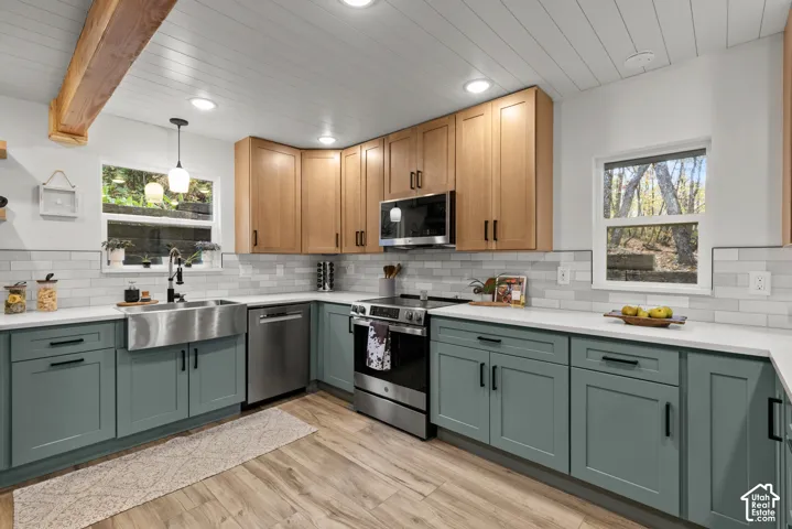 Kitchen featuring wood-finish flooring, two-tone cabinetry, stainless steel appliances, a farmhouse sink, and white subway tile backsplash