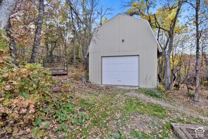 Detached outbuilding with a gambrel roof and a white overhead garage door