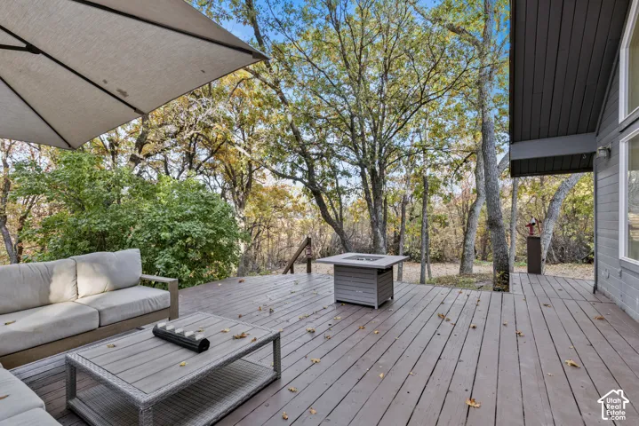 Spacious outdoor deck with a built-in fire pit, surrounded by mature trees