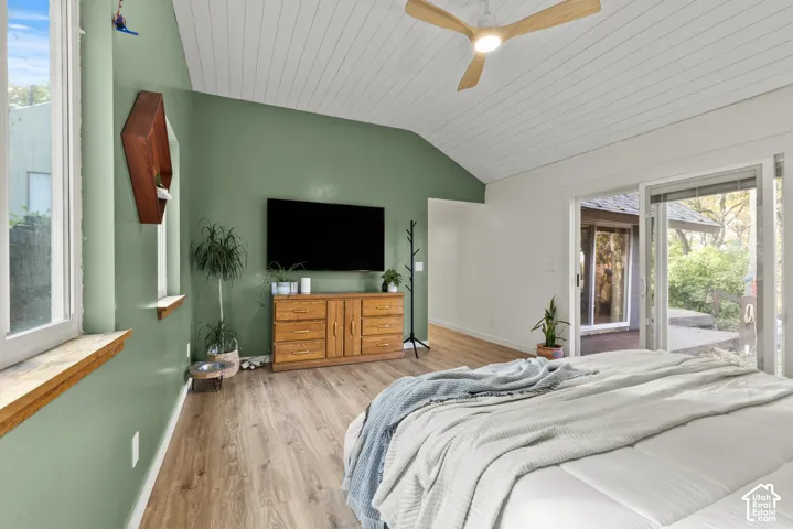 Vaulted ceiling with wood-finish planks, wood-finish flooring, ceiling fan with integrated lighting, built-in shelving, and sliding glass door