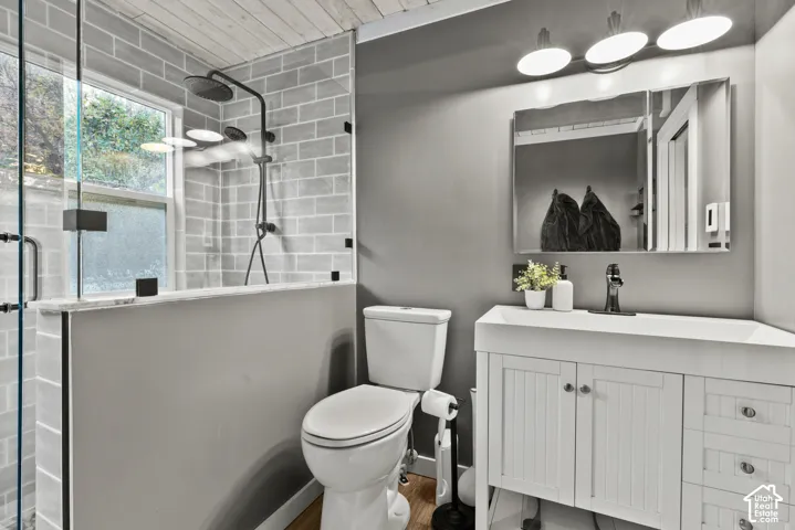 Shower with light gray subway tile surround, matte black rainfall showerhead, and glass enclosure