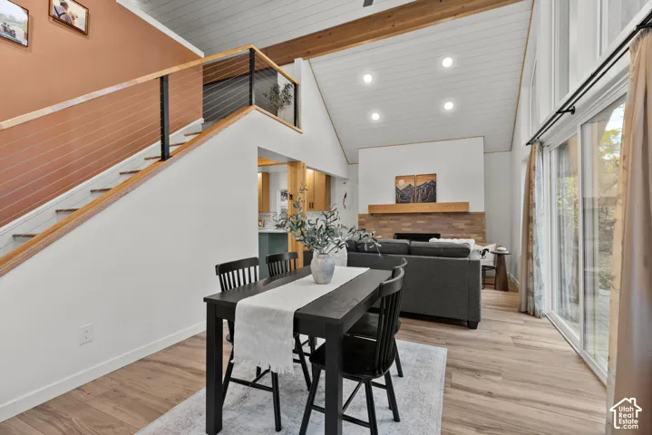 Vaulted ceiling with exposed wood beams, wood-finish flooring, and a fireplace with a wood mantel