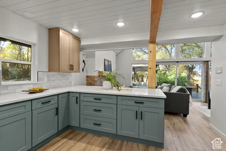 Modern kitchen featuring wood-finish flooring, white countertops, shaker-style cabinetry, and a subway tile backsplash