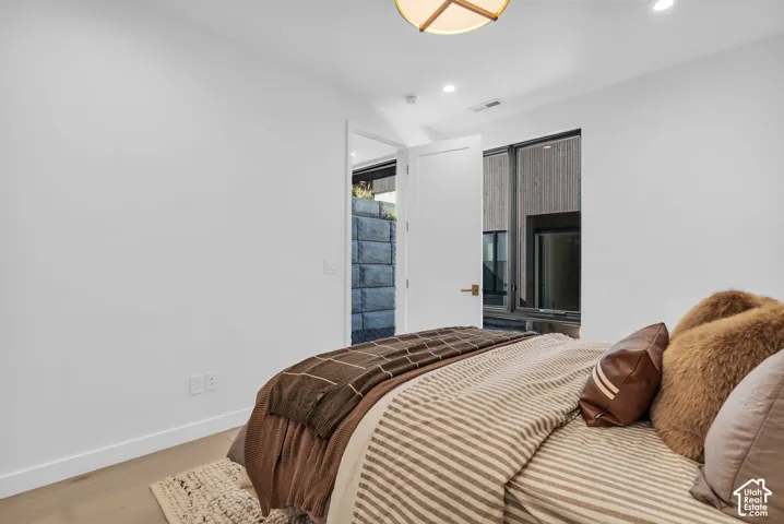 Recessed lighting, light wood-finish flooring, white walls, modern ceiling fixture, and exterior window