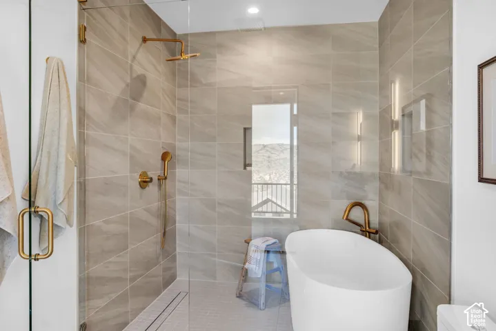 Enclosed shower with a linear drain, a freestanding soaking tub, a wall-mounted tub filler, and a large window