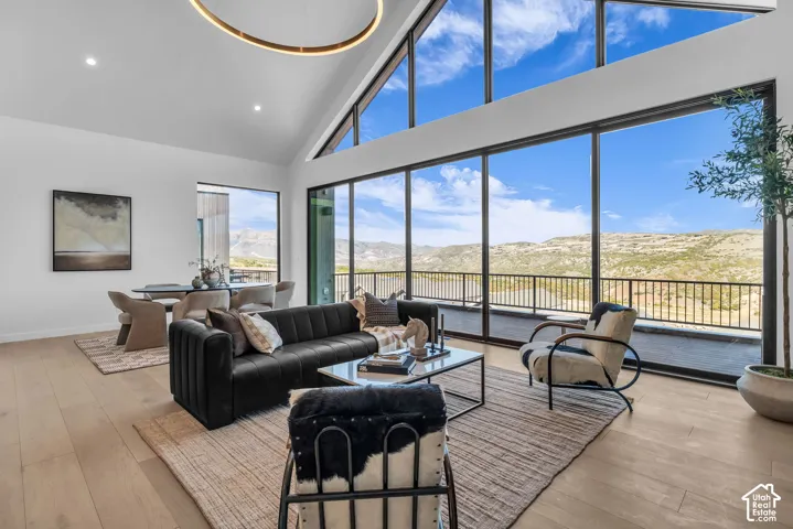 Vaulted ceilings with recessed lighting, expansive floor-to-ceiling windows, wood-finish flooring, and a contemporary circular chandelier