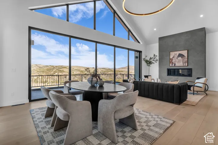 Expansive floor-to-ceiling windows, vaulted ceilings, a built-in fireplace, recessed lighting, and wood-finish flooring