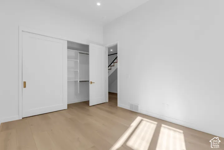 Wood-finish flooring throughout, white walls, and a built-in closet with shelving