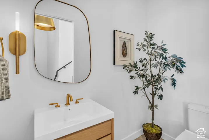 Floating wood-finish vanity with an integrated rectangular sink and brass-finish faucet