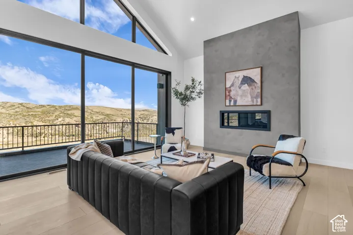 Expansive floor-to-ceiling windows, soaring vaulted ceilings, a contemporary built-in fireplace, durable wood-finish flooring, and a large outdoor balcony