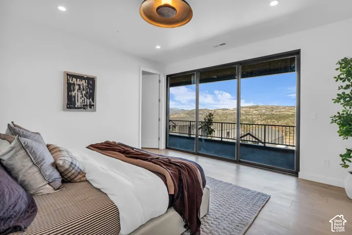 Expansive sliding glass doors, recessed lighting, wood-finish flooring, and a contemporary ceiling fixture