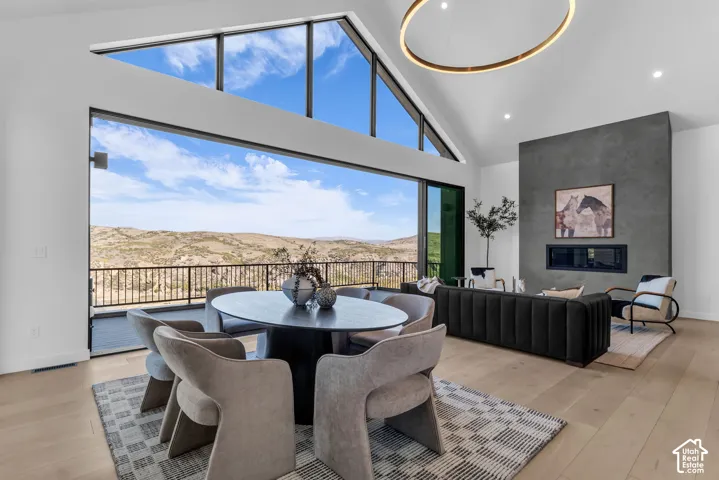 Vaulted ceilings with clerestory windows, expansive sliding glass doors, light wood-finish flooring, and a floor-to-ceiling fireplace with a linear insert